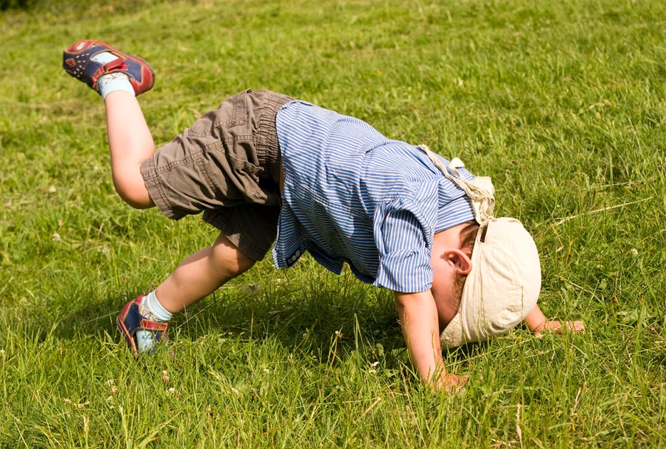 Barn slår kolbøtte i græsset. Foto: Colourbox